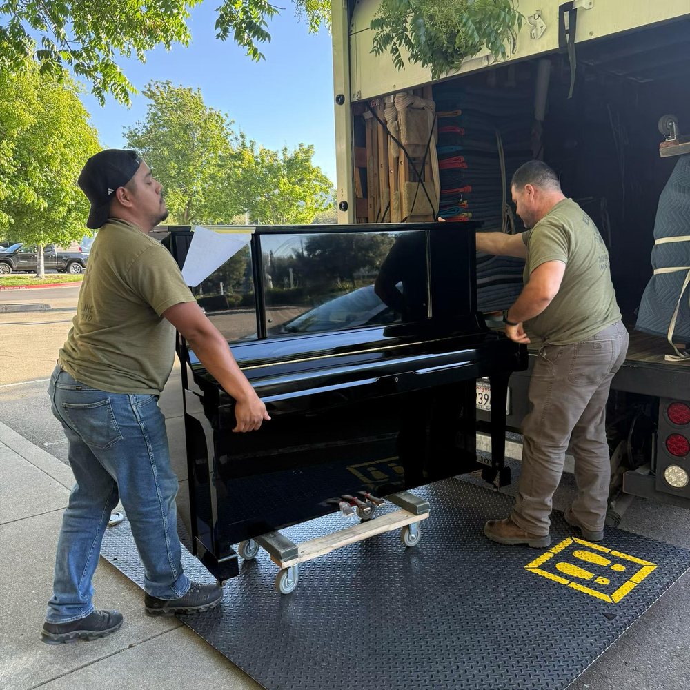 Professional movers loading a piano for white-glove transport