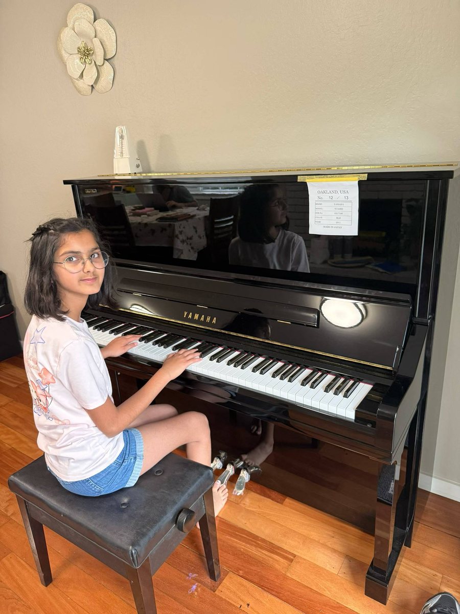 A young student playing her Yamaha upright piano at home